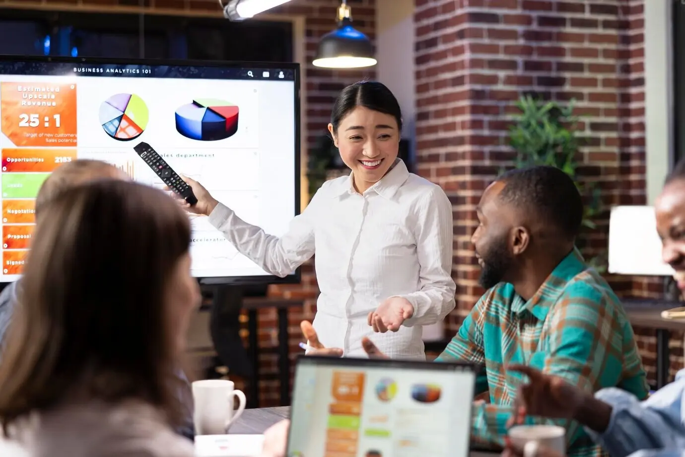 Fröhliche/r Unternehmer/in, der/die mit Kolleginnen und Kollegen Ideen brainstormt.